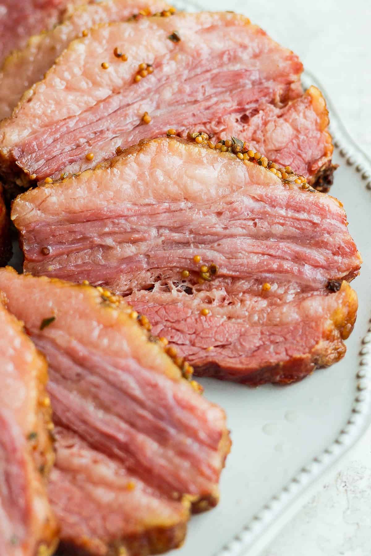 Slices of smoked corned beef on a white plate.