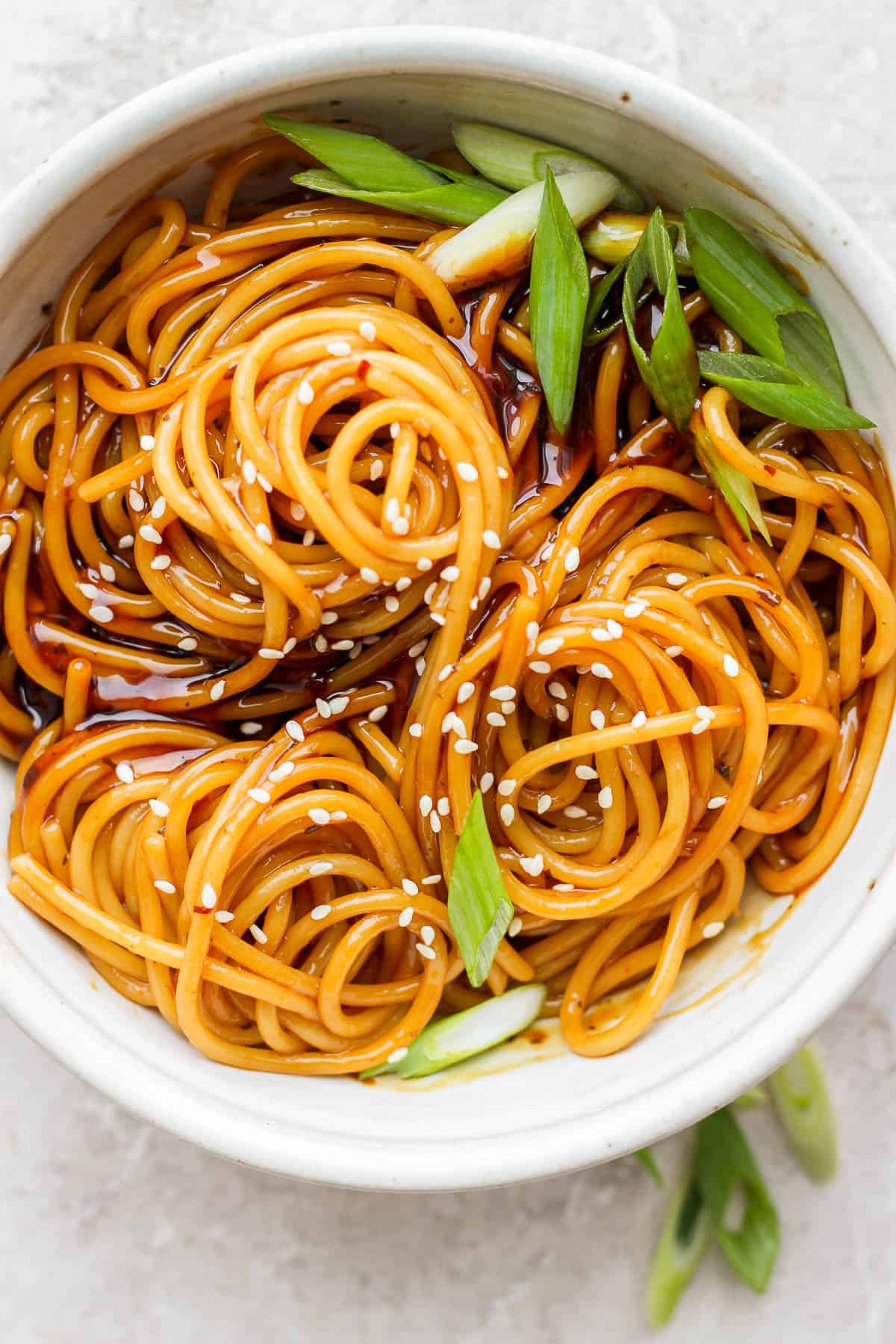 Teriyaki noodles in a bowl with sesame seeds and chopped green onions.