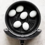 Top down shot of 6 eggs sitting in an air fryer.