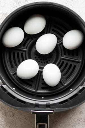 Top down shot of 6 eggs sitting in an air fryer.