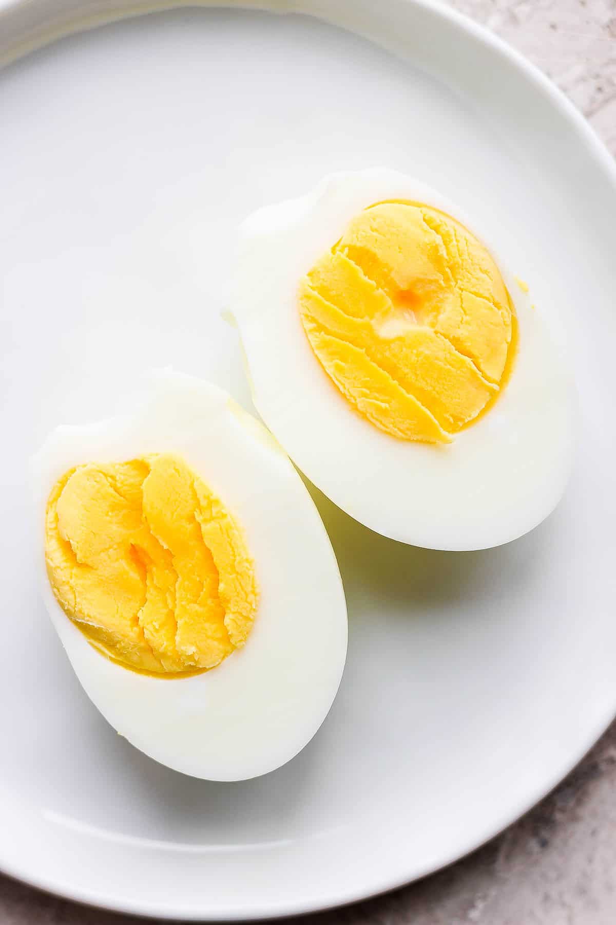 An air fryer hard boiled egg cut in half on a plate.