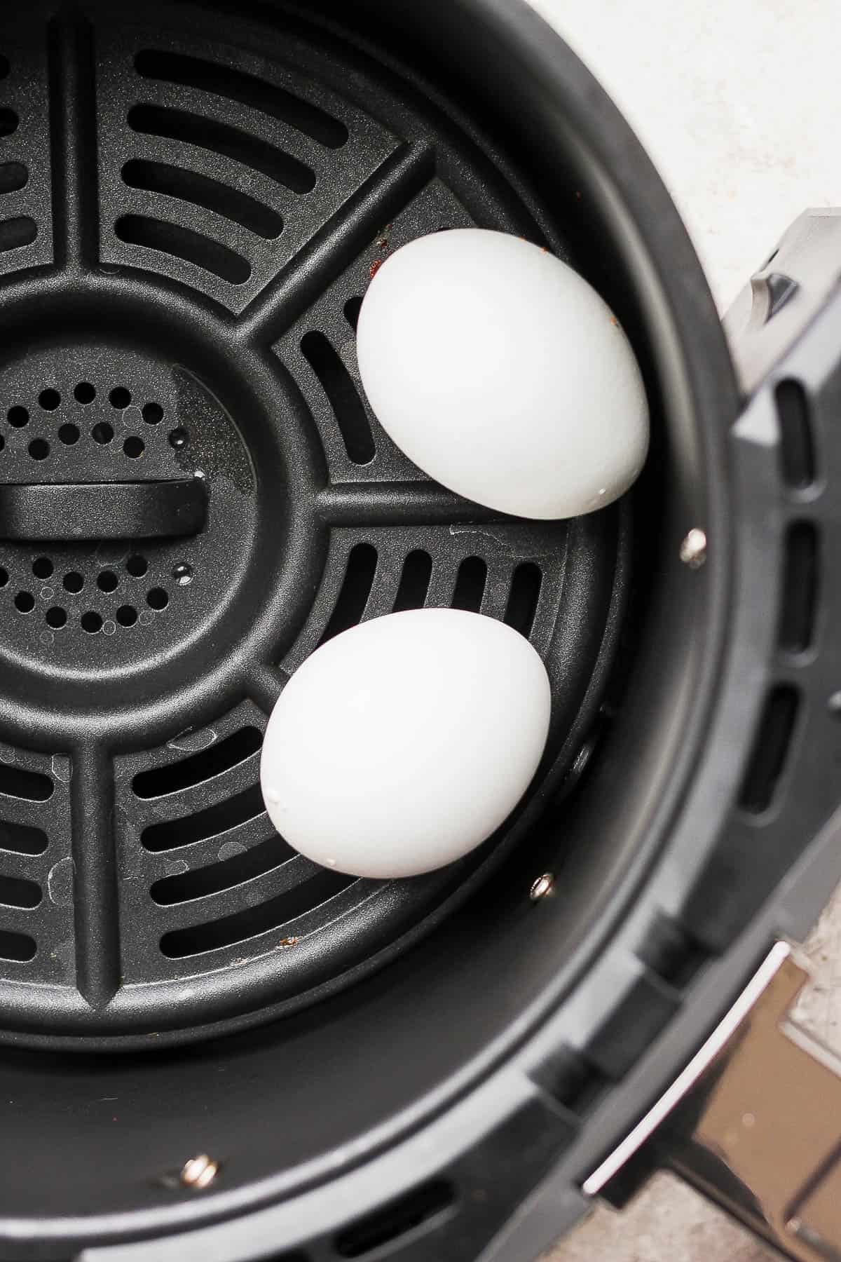2 eggs in an air fryer basket.