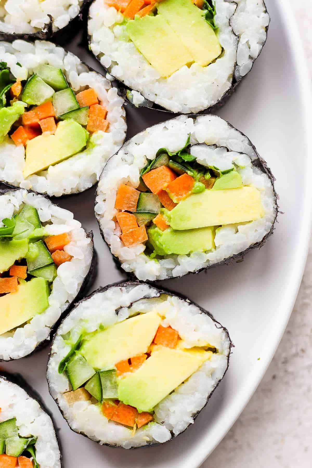 Pieces of an avocado roll on a white plate.