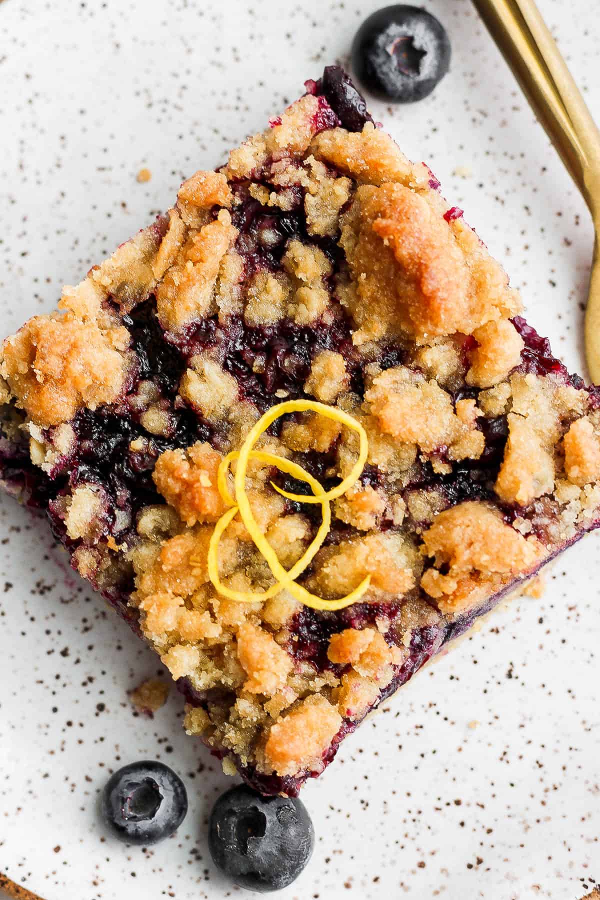 A blueberry crumb bar on a small plate with a fork.