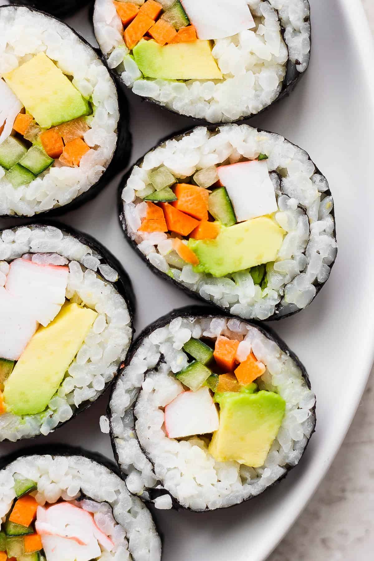 Pieces of a California roll on a white plate.