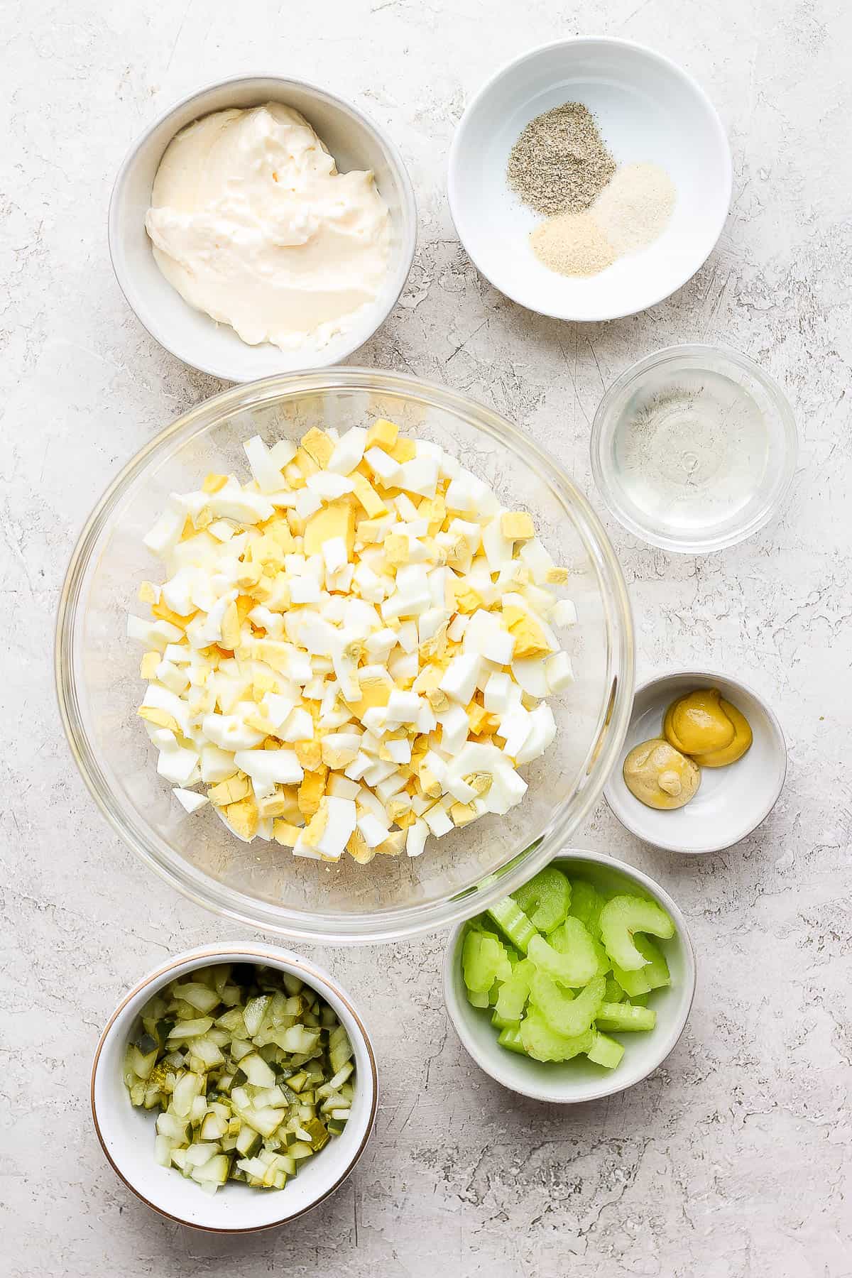 Ingredients for egg salad in separate dishes.