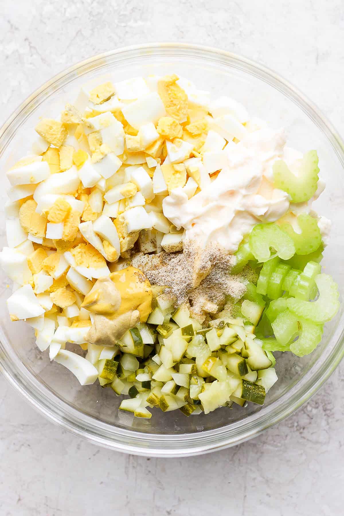 All of the egg salad ingredients in one glass bowl.