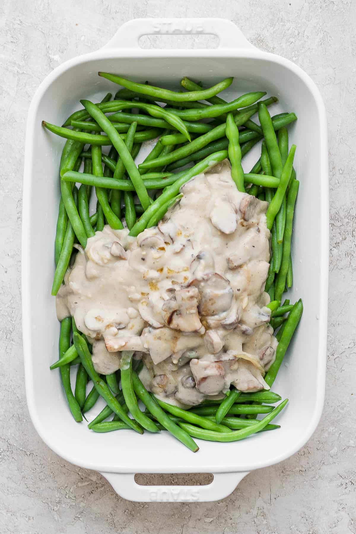 Mushroom sauce poured over the blanched green beans in a baking dish.