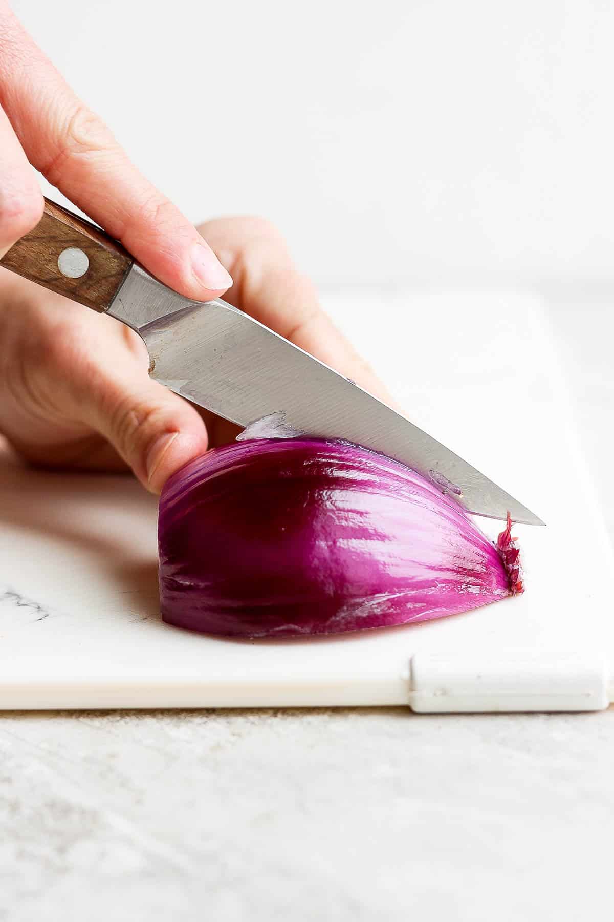 Half of a red onion being cut in half again.