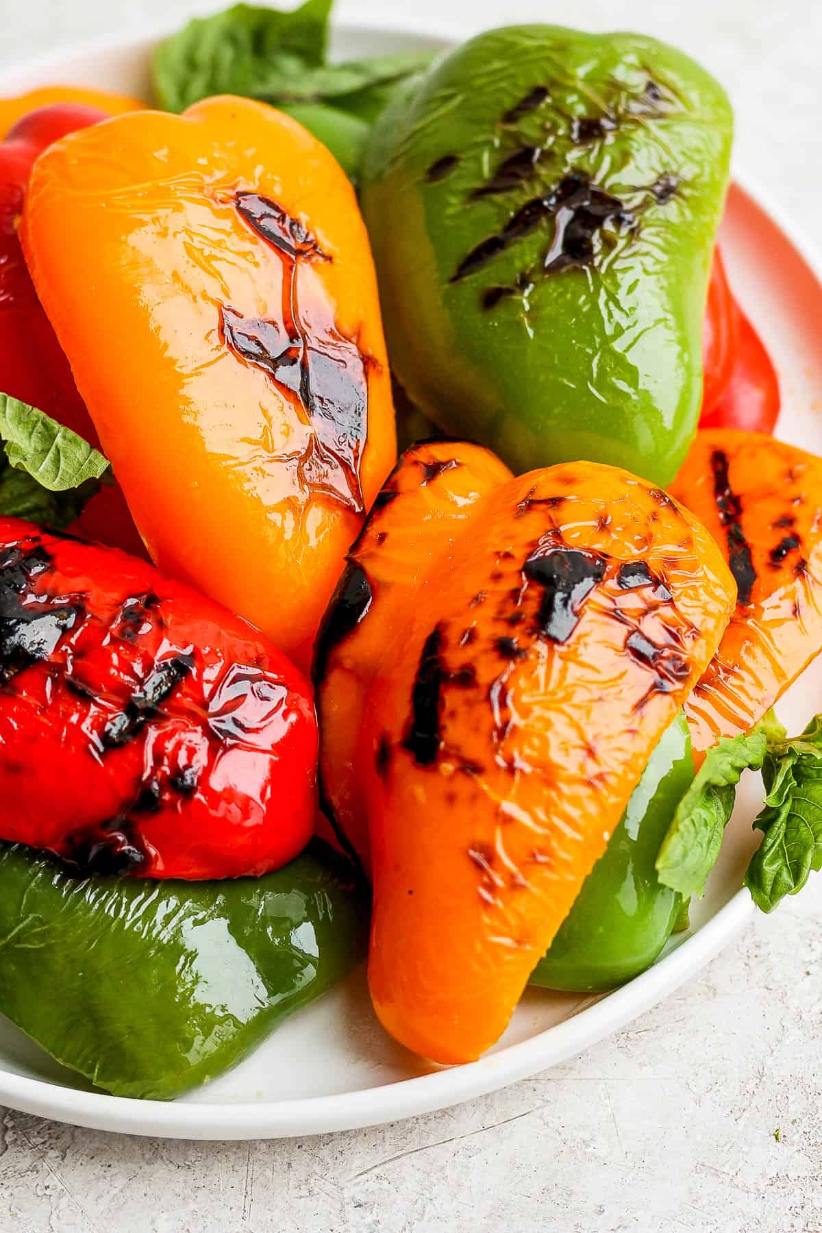 A pile of grilled peppers on a large white plate.