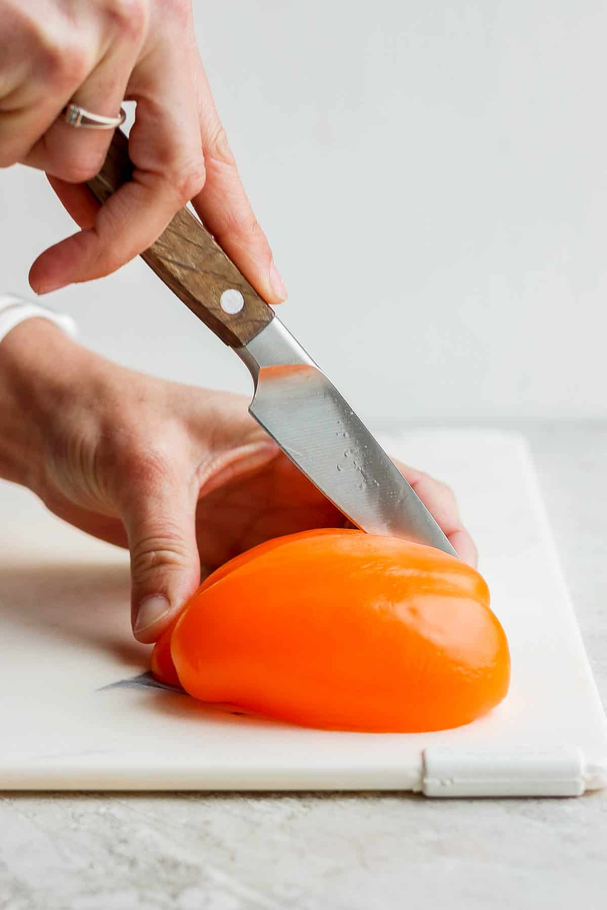 One half of a bell pepper being cut in half again to make quarters.