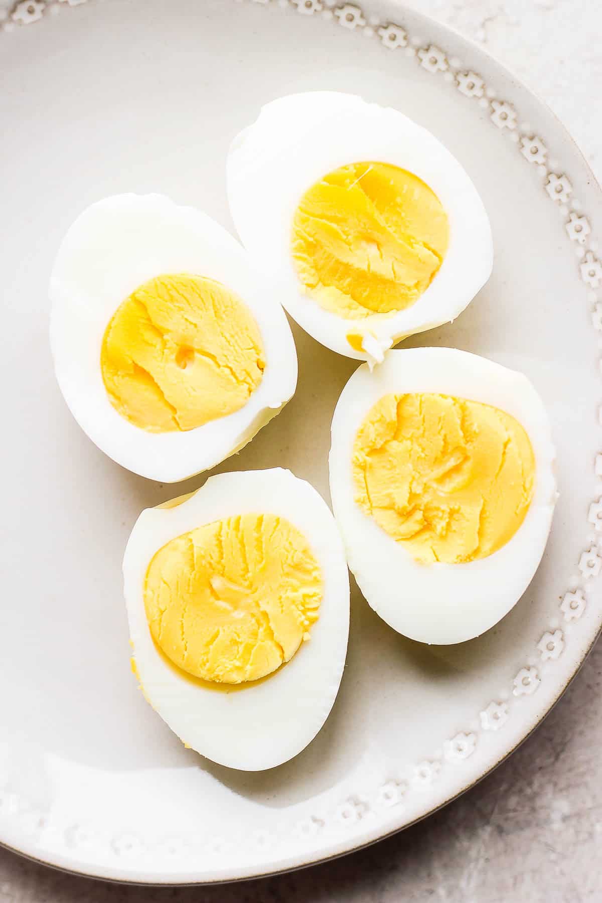 Two hard boiled eggs, cut lengthwise, on a plate.