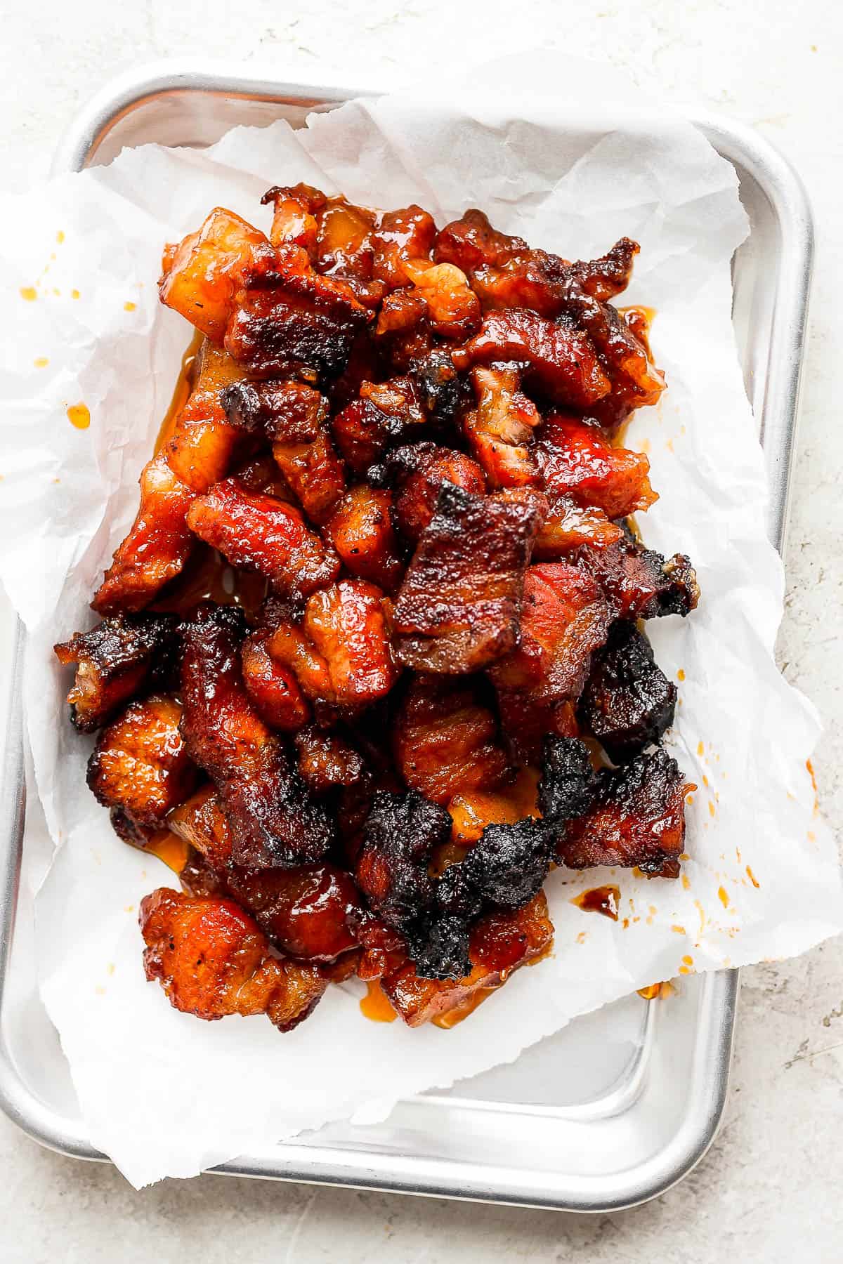 Pork belly burnt ends on parchment paper on a tray for serving.