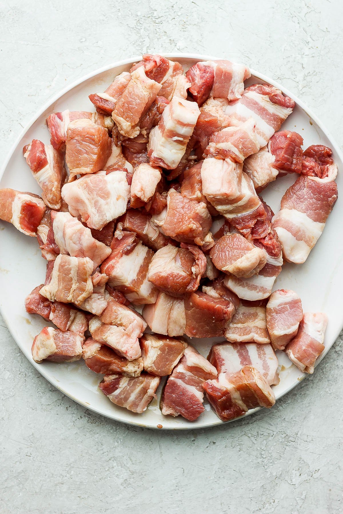 Large pieces of pork belly on a white plate.