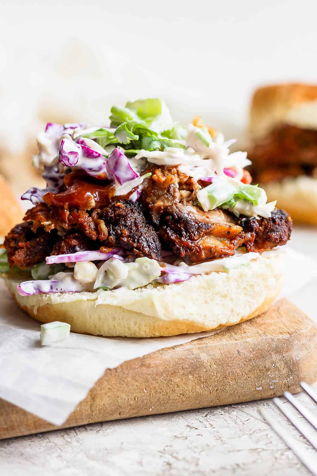 The bottom bun topped with pulled pork, bbq sauce, and coleslaw.