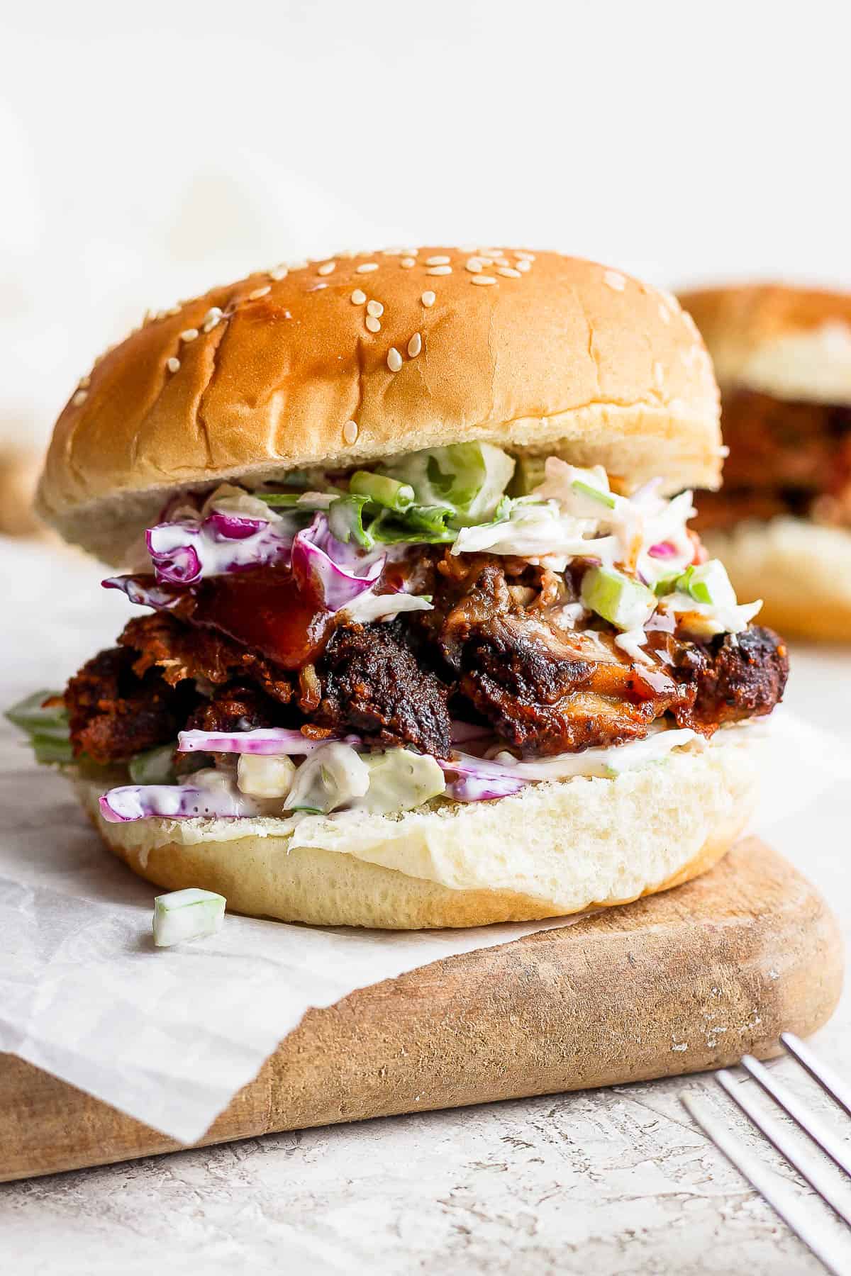 A pulled pork sandwich on a piece of parchment paper.