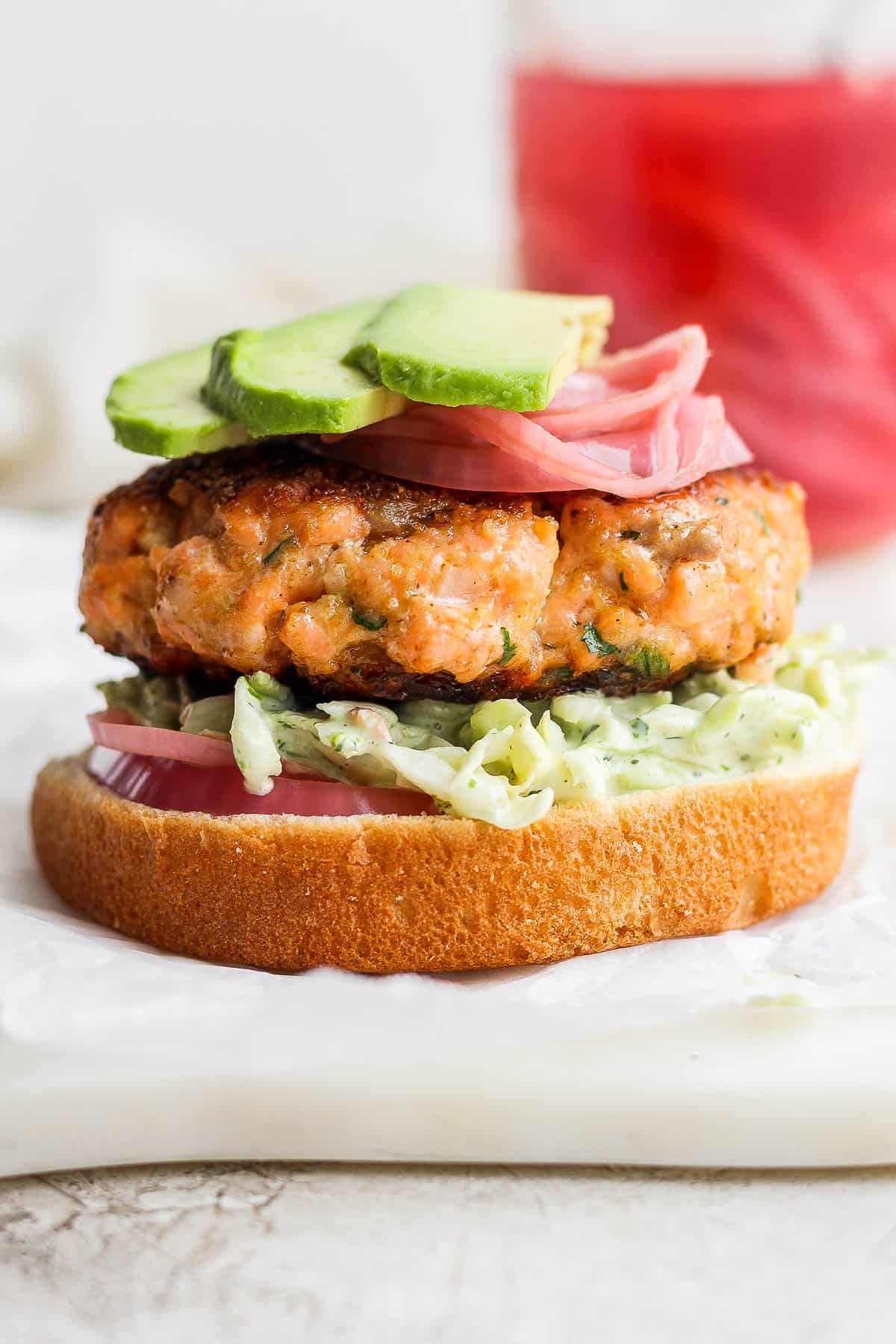 A salmon burger on a bottom bun with all the toppings.