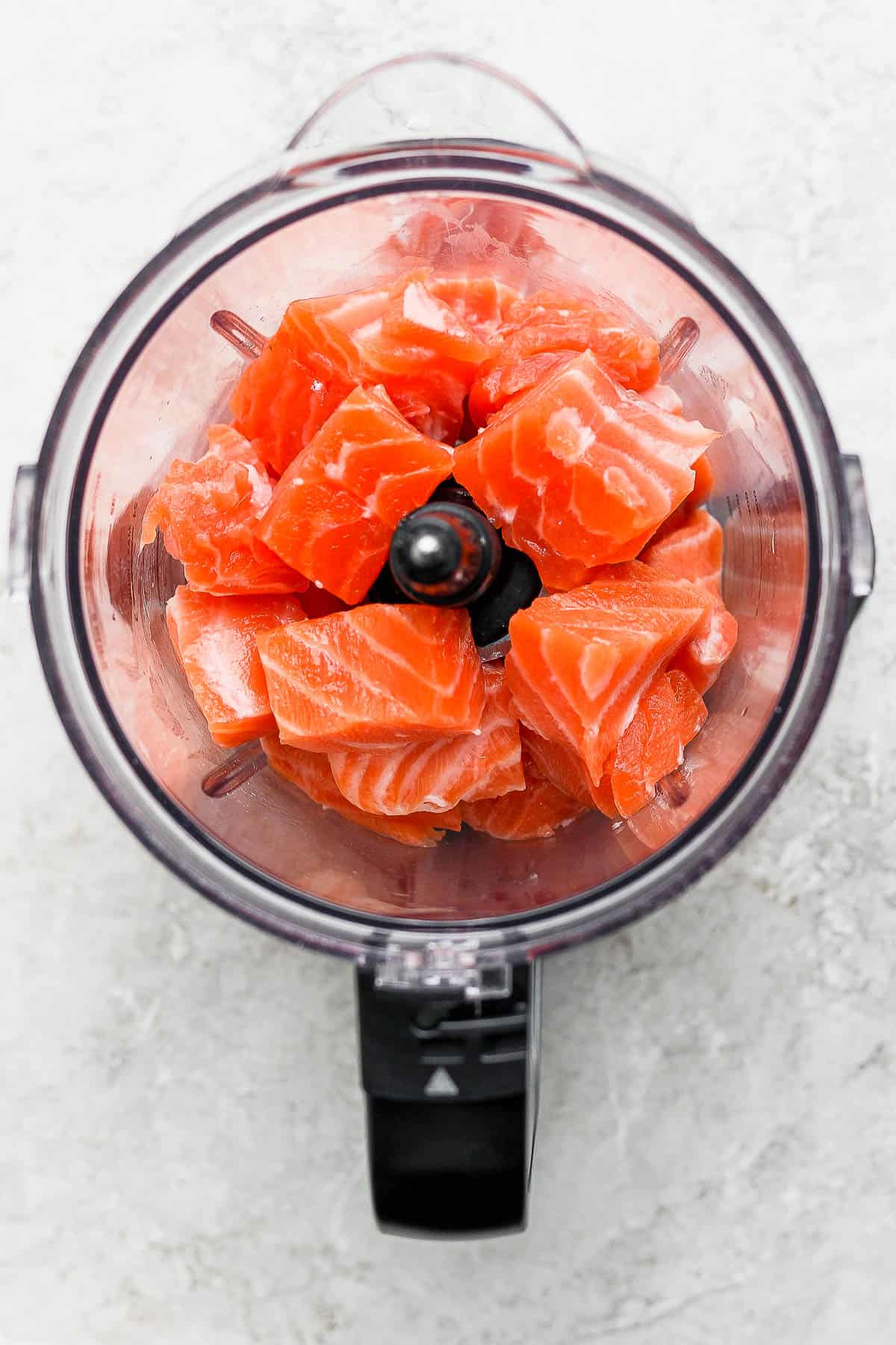 Large chunks of salmon in a food processor.
