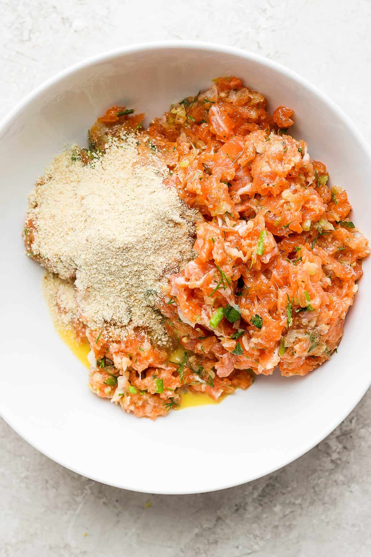 Salmon mixture in a bowl with some breadcrumbs.