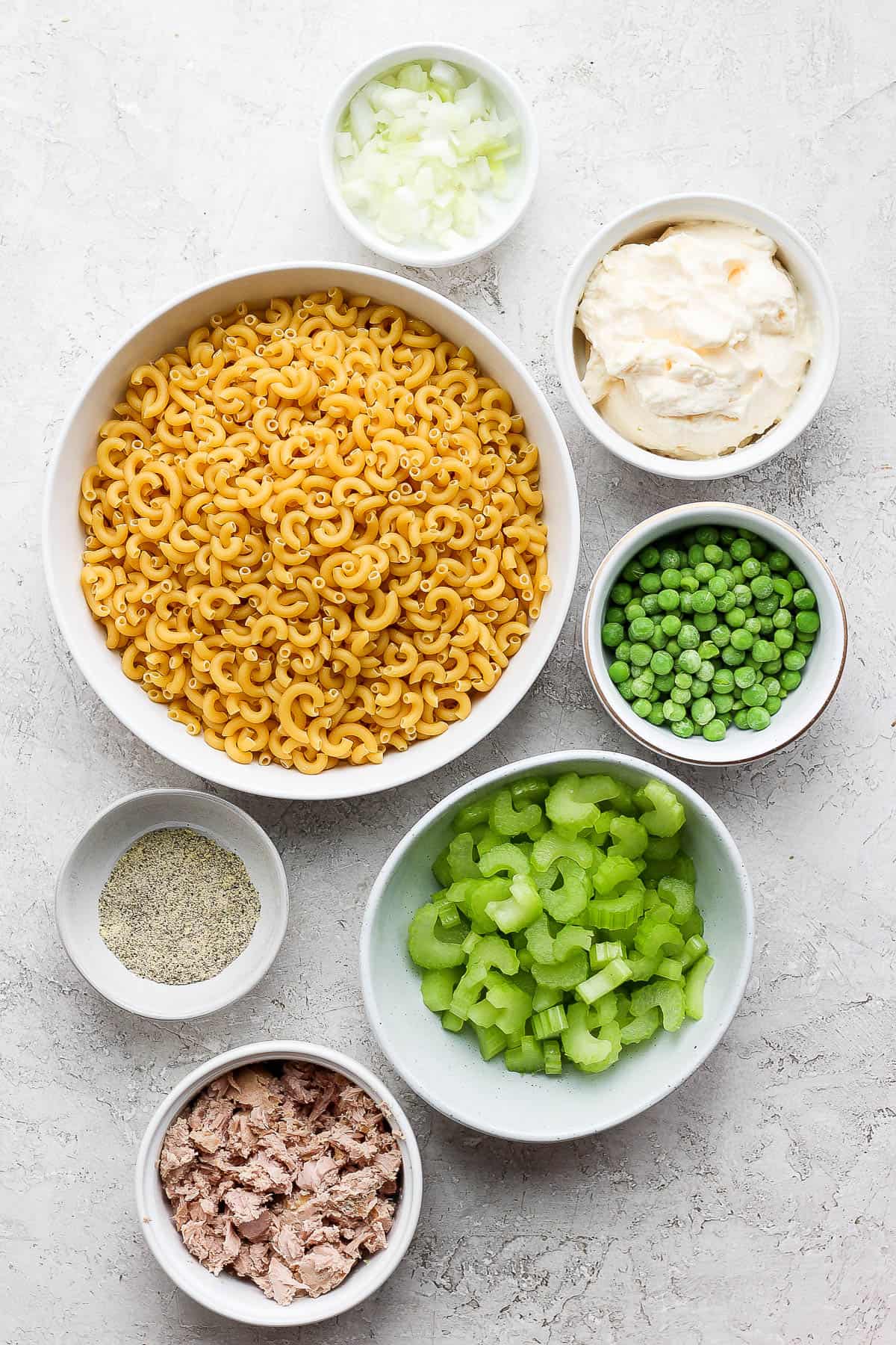 All of the tuna macaroni salad ingredients in separate bowls.