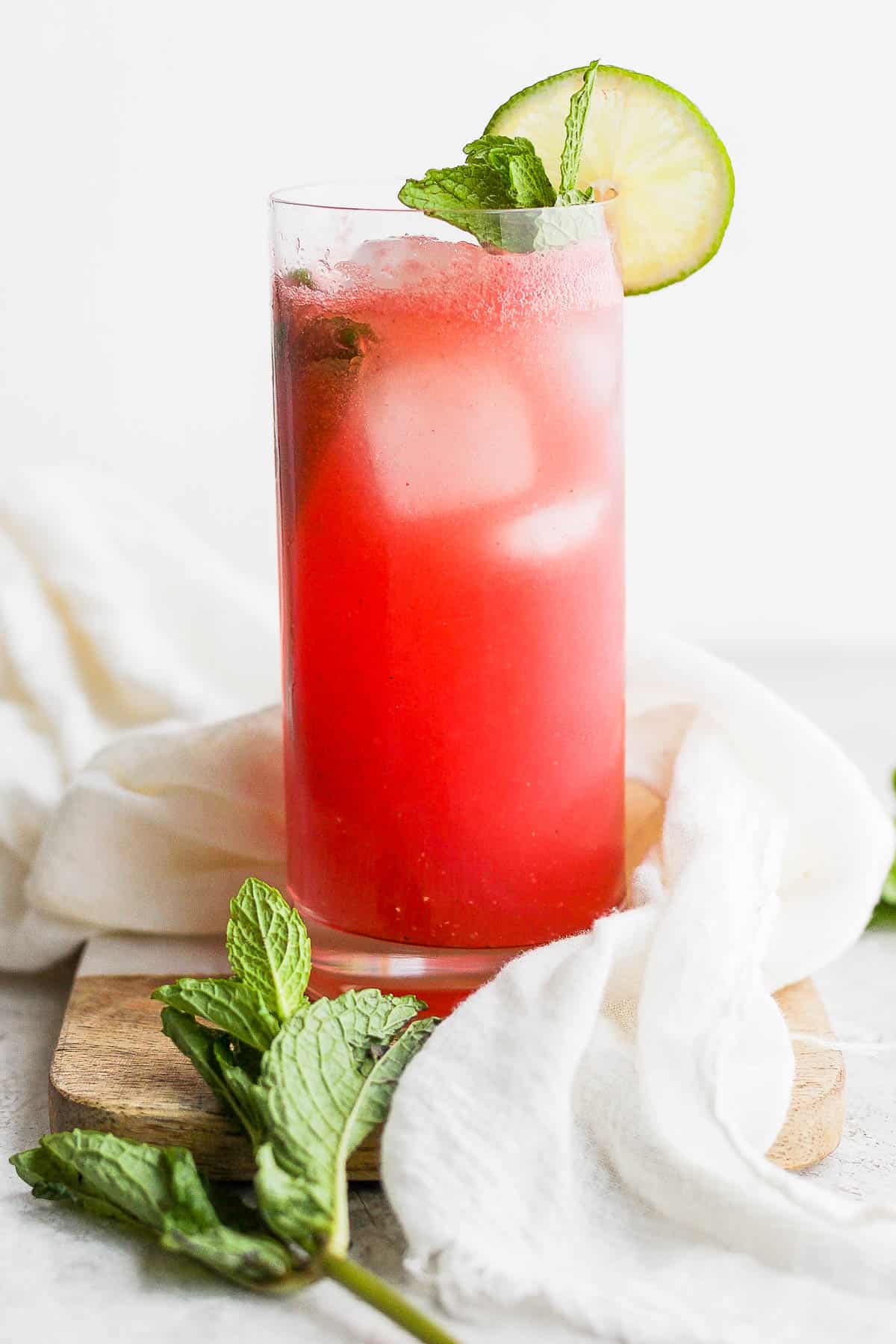 A glass of watermelon spritzer with mint and a slice of lime for garnish.