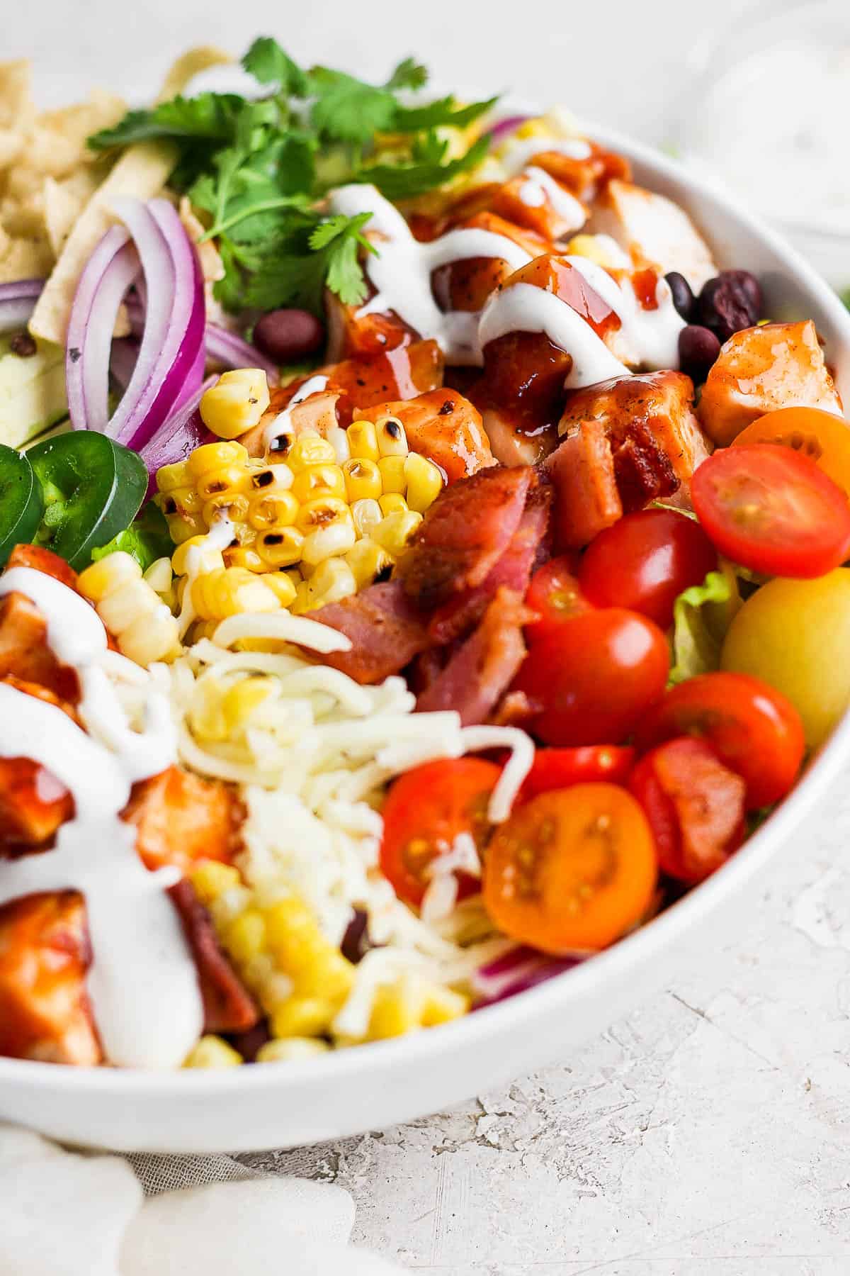 A bbq chicken salad assembled in a white bowl.