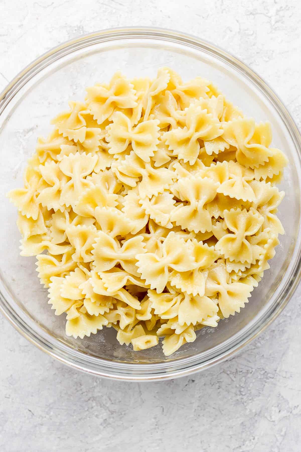 Cooked bowtie noodles in a large glass bowl.