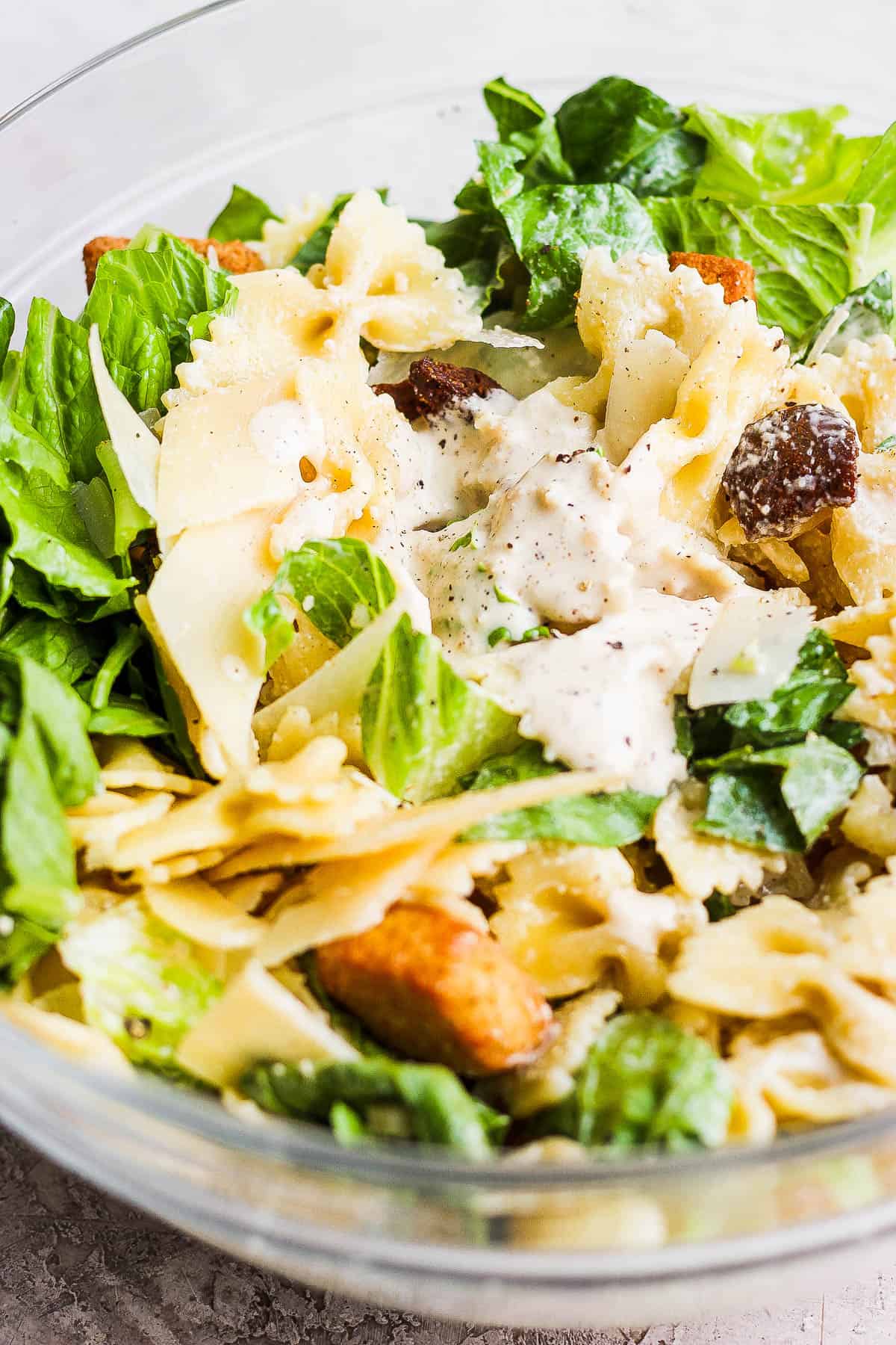 Caesar pasta salad all mixed together in a large bowl.
