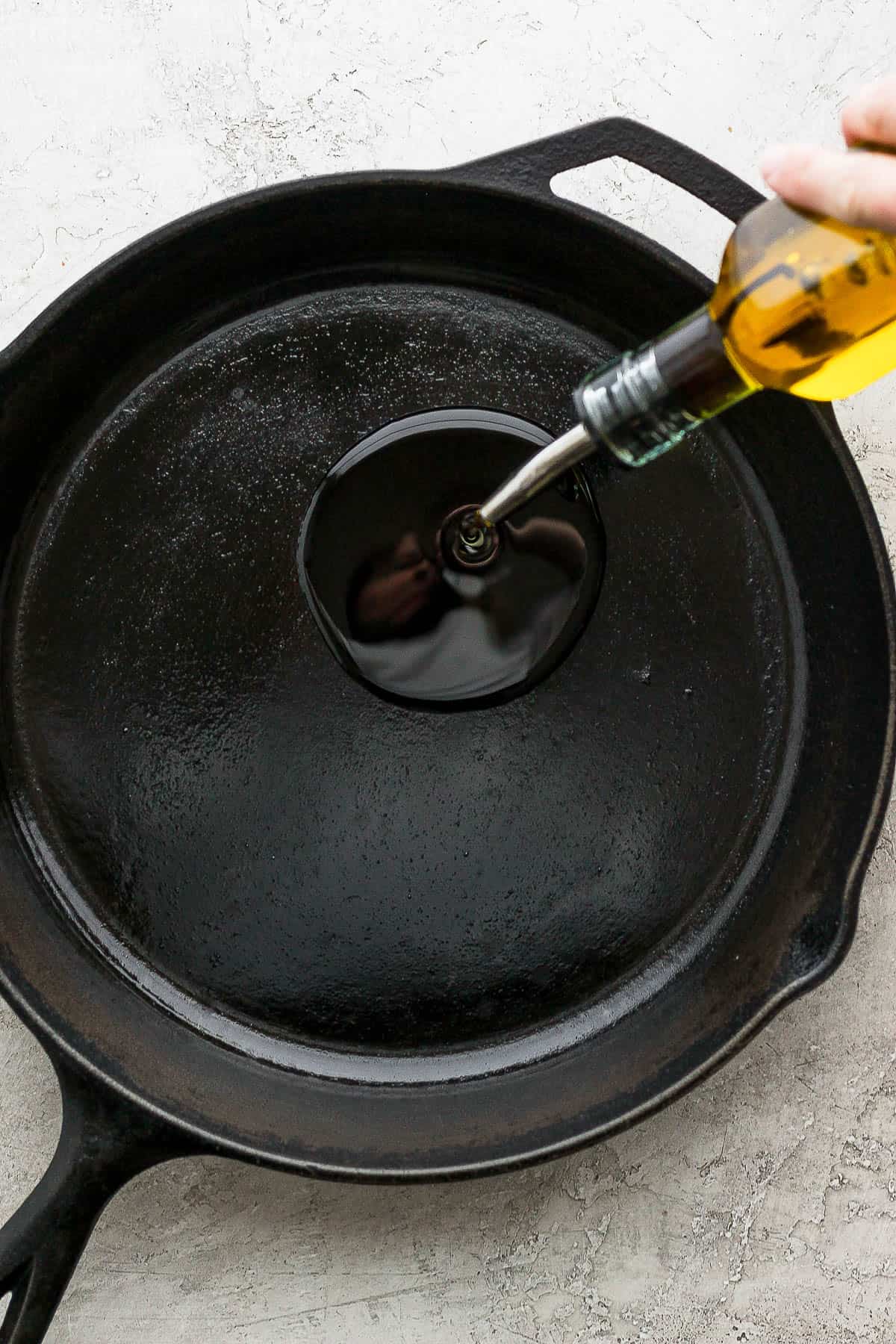 Olive oil being pouring into a large skillet.
