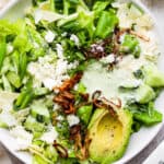 Top down shot of a bowl of green goddess salad with crispy shallots, avocado and green goddess dressing.