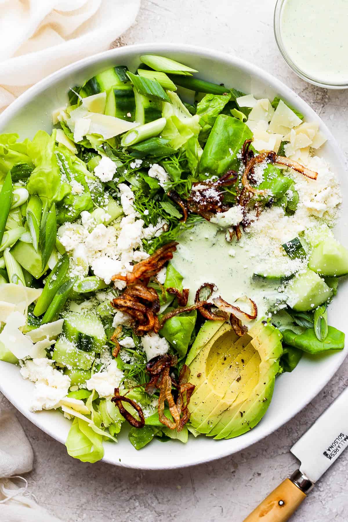 The most amazing green goddess salad in a white bowl.