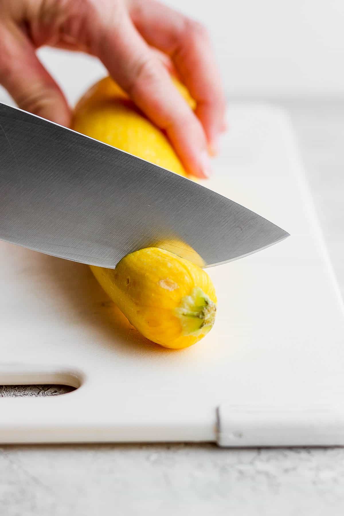 The top being cut off of a yellow squash.