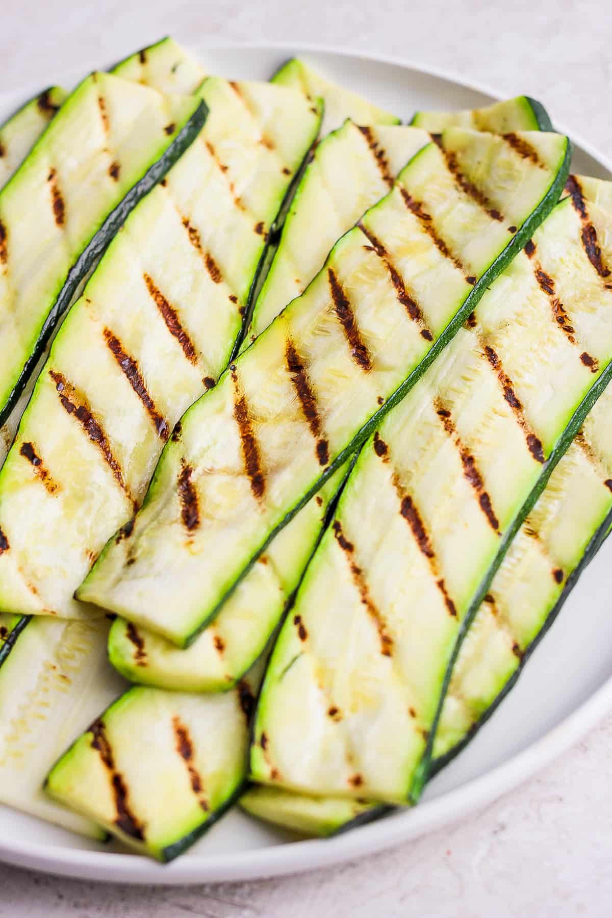 Grilled zucchini piled on a plate.