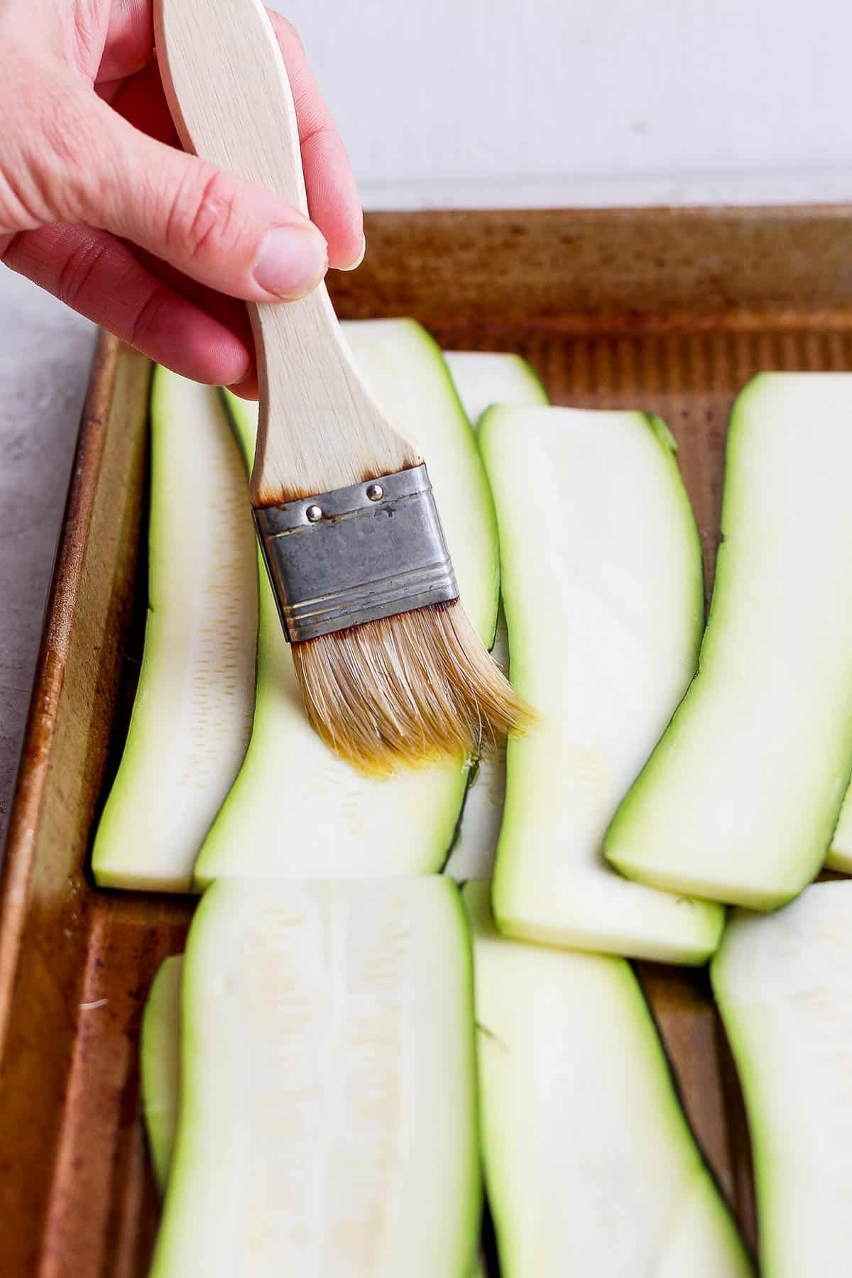 Olive oil being brushed on the zucchini.