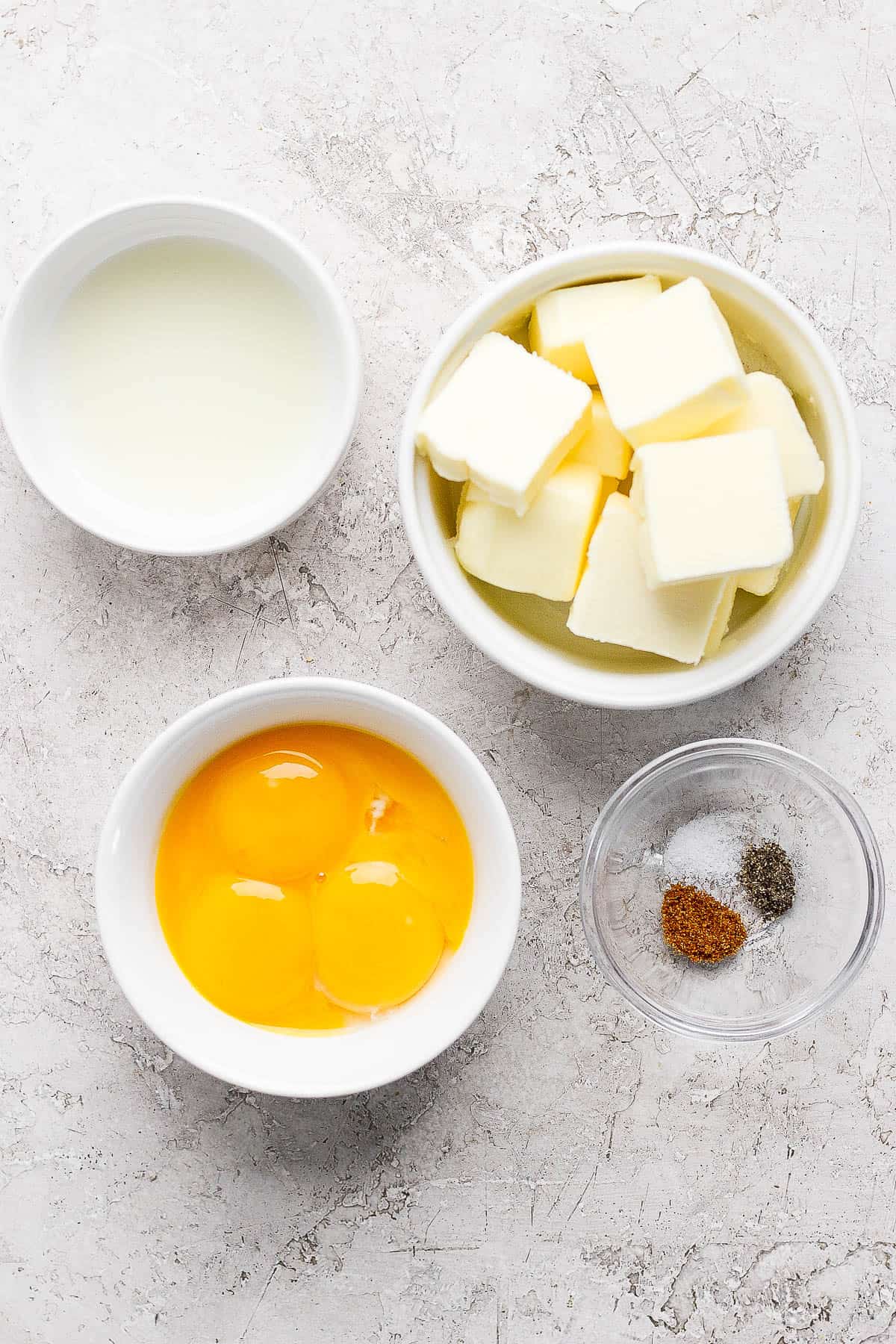The ingredients for hollandaise sauce in separate bowls.