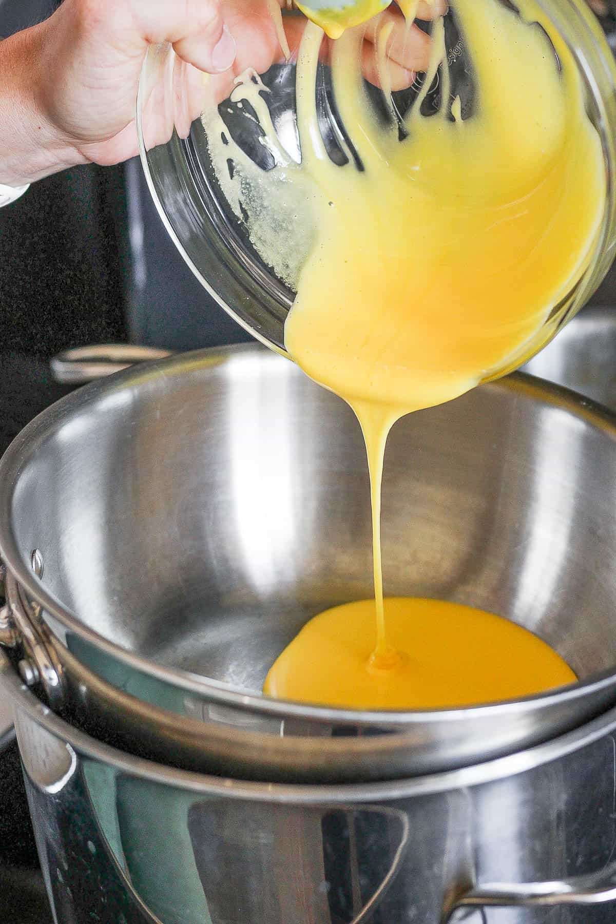 Egg yolk mixture being poured into the top of the double boiler.
