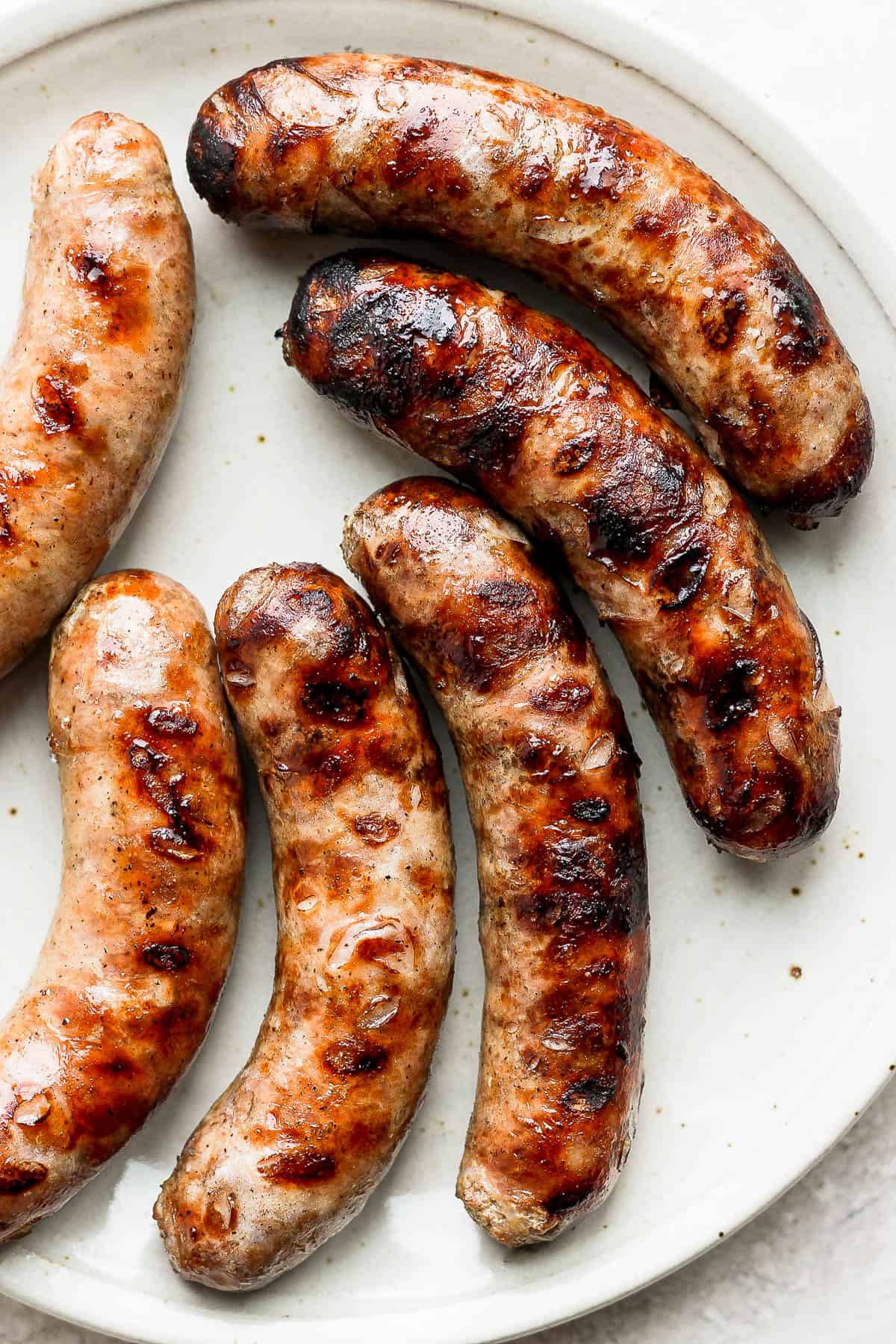 Perfectly grilled brats on a large platter.