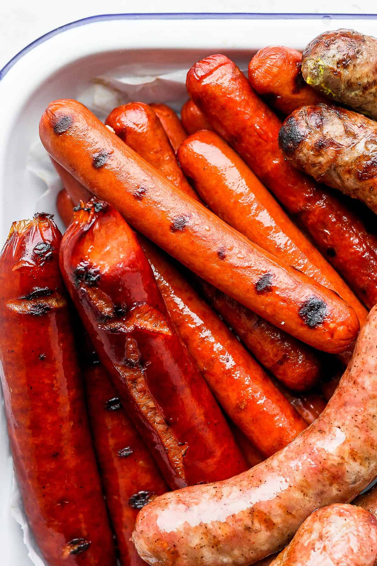 Grilled hot dogs and grilled brats in a large tray.