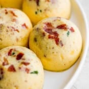 Side shot of an Instant Pot Egg Bite on a plate with bacon and spinach showing.