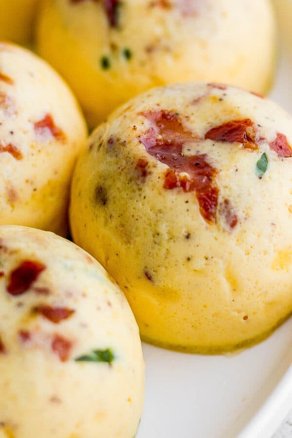 Side shot of an Instant Pot Egg Bite on a plate with bacon and spinach showing.