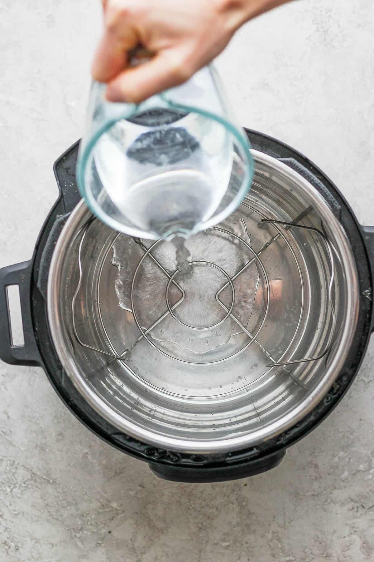 The trivet in the bottom of the Instant Pot and cold water being poured in.