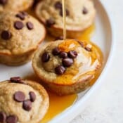 A plate of pancake bites with maple syrup being drizzled on top.