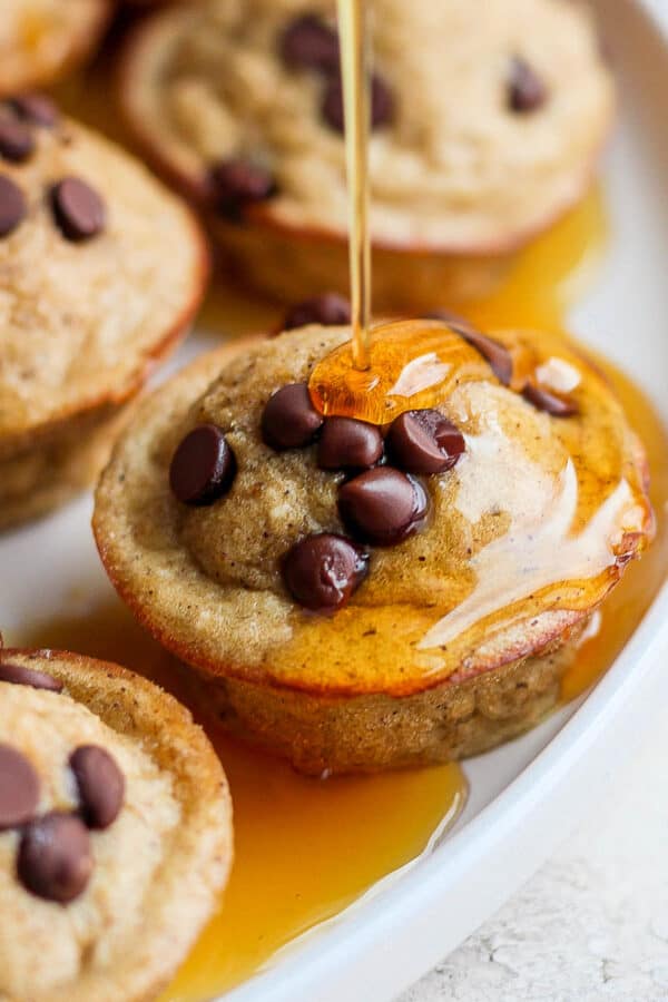 A plate of pancake bites with maple syrup being drizzled on top.
