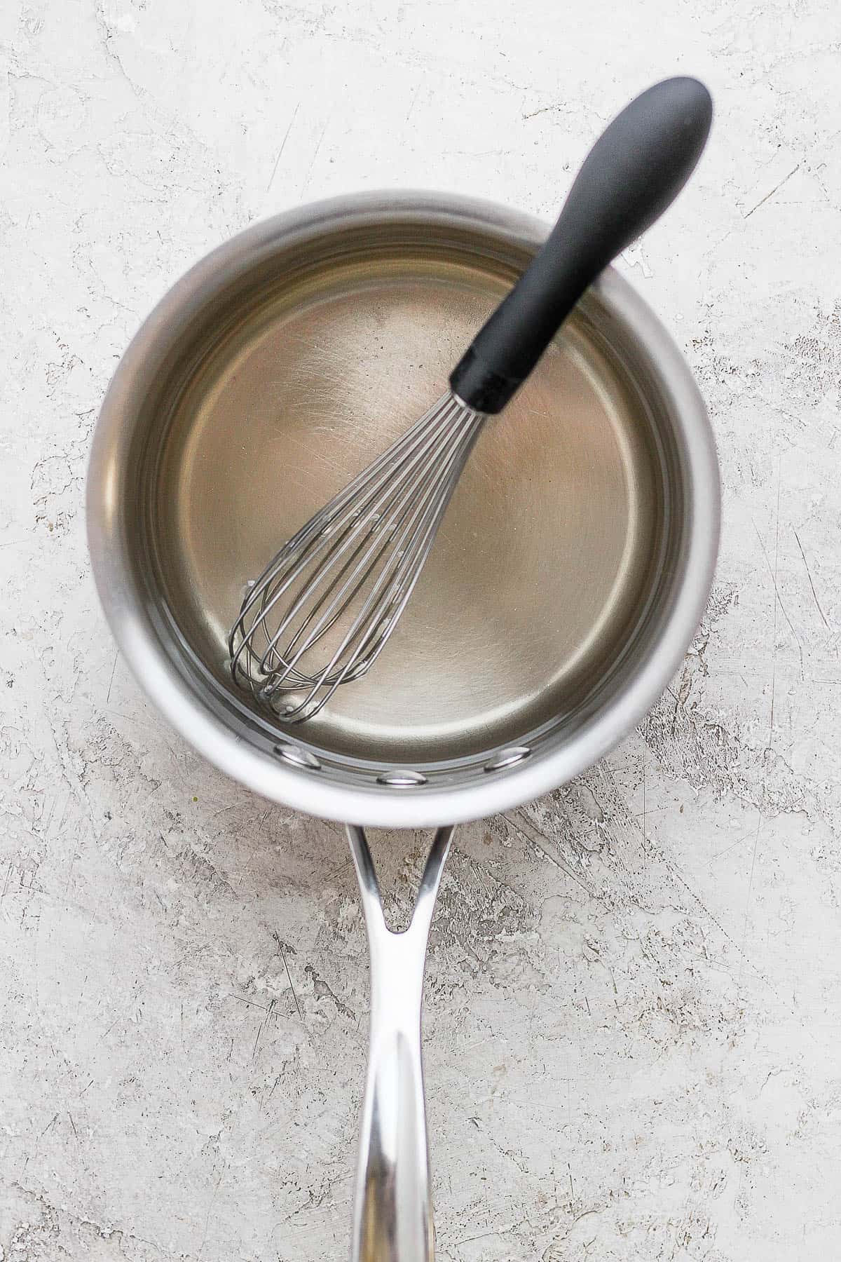 A whisk in the medium sized sauce pan with dissolved sugar into the water. 