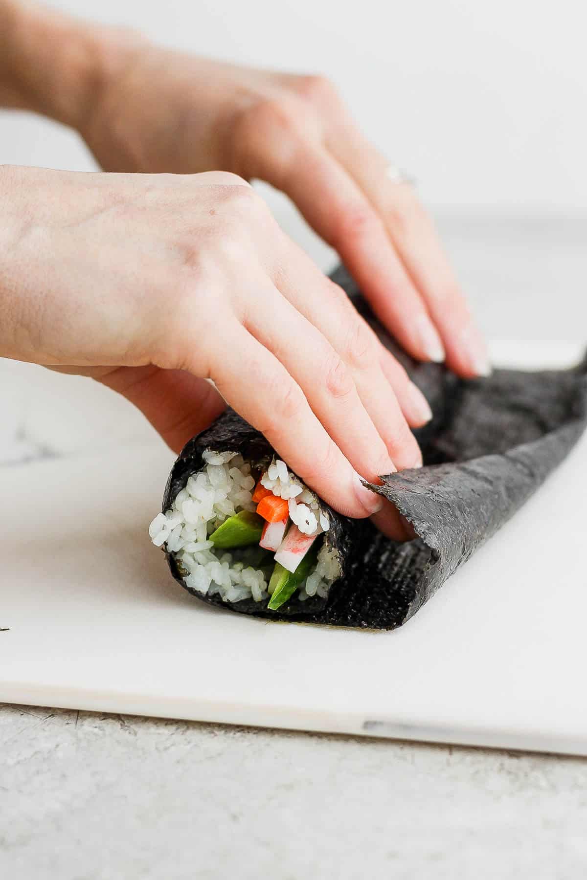 Two hands rolling the sushi burrito.