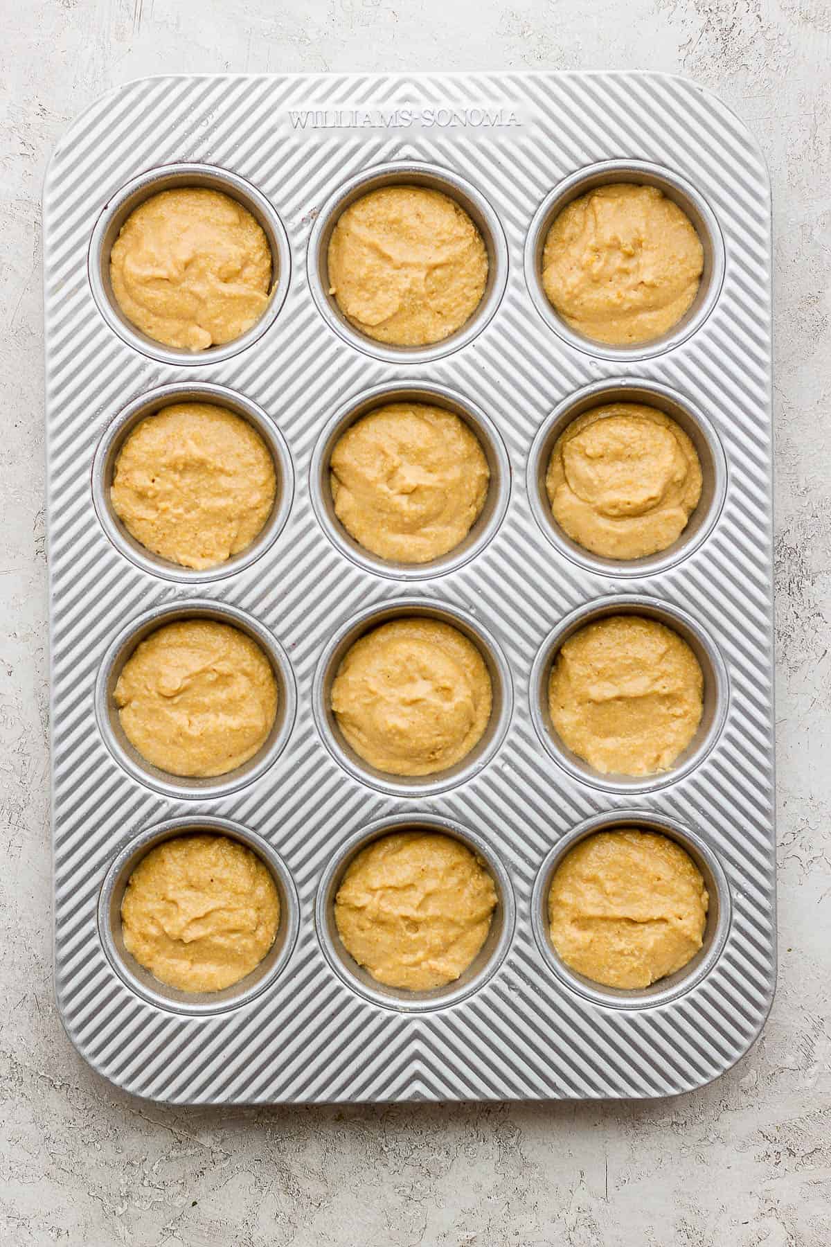 The cornbread batter in a muffin tin before baking.
