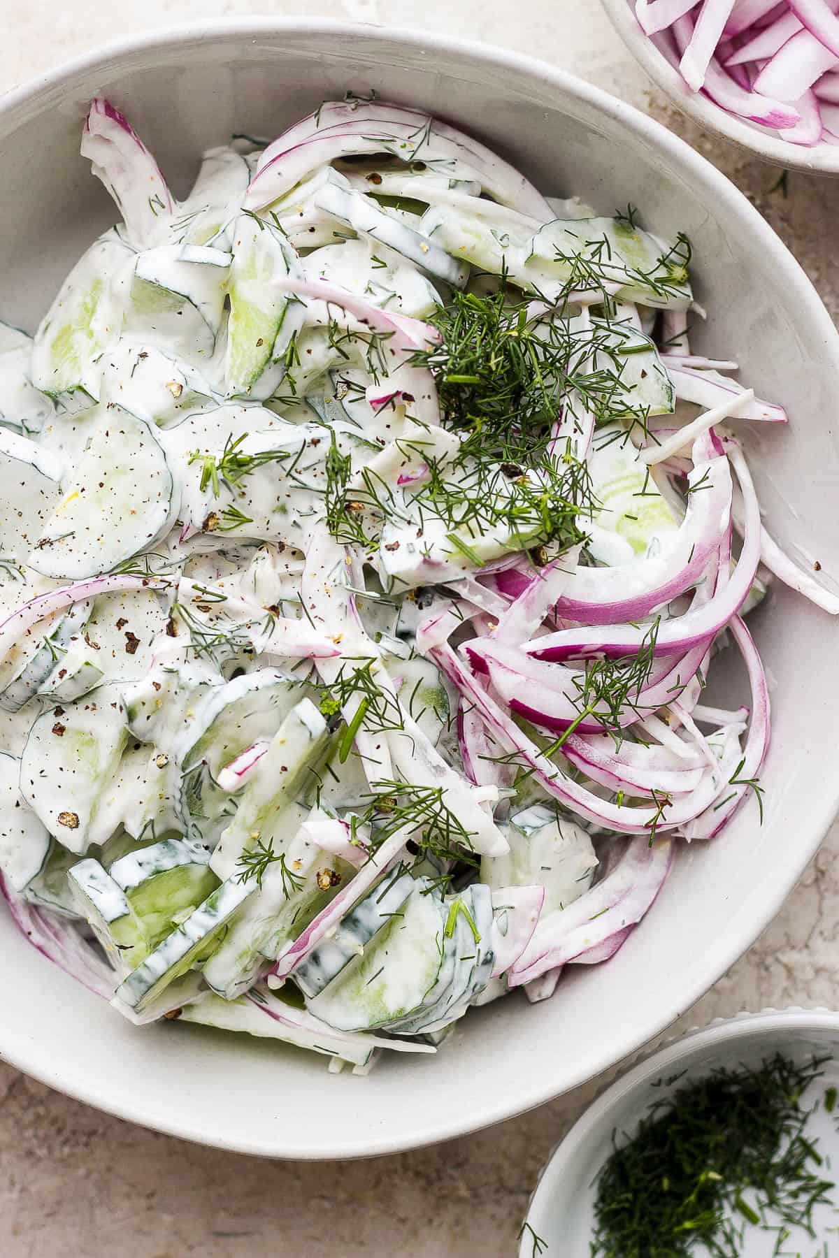 Creamy cucumber salad in a bowl topped with fresh chopped dill.