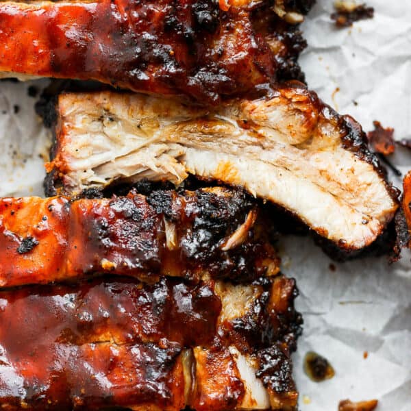 Close up shot of a rack of grilled ribs with bbq sauce with one rib flipped so the juicy cut side is up.