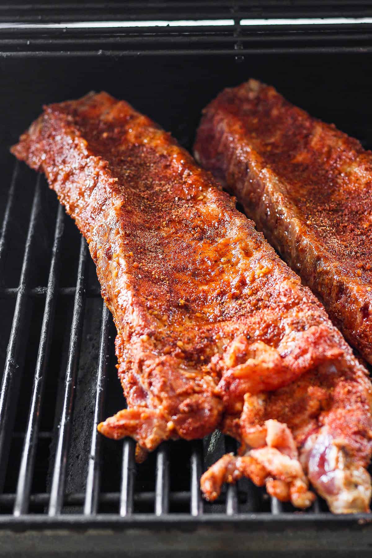 Seasoned ribs on the hot grill grates.
