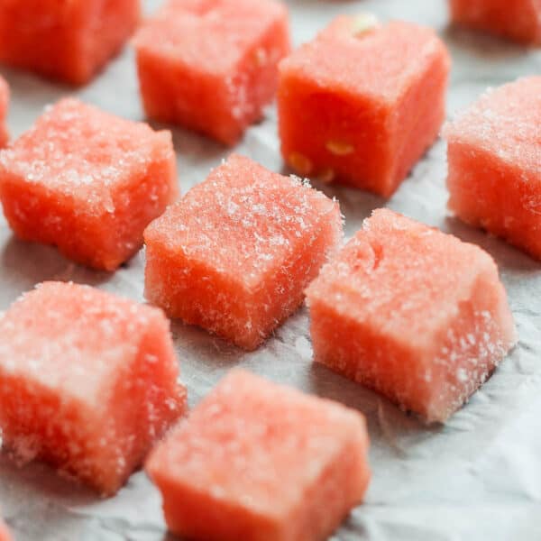 Several pieces of frozen watermelon on a parchment-lined baking sheet.